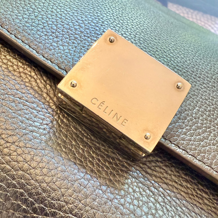Close-up of a Céline handbag with gold plaque on a textured surface