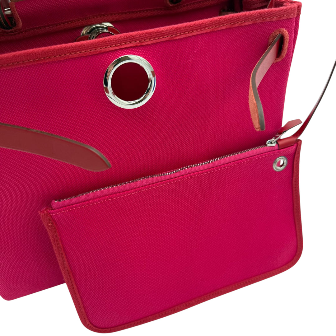 Bright pink textured tote bag with a matching zippered pouch, featuring silver-tone metal hardware and brown leather accents on a white background.