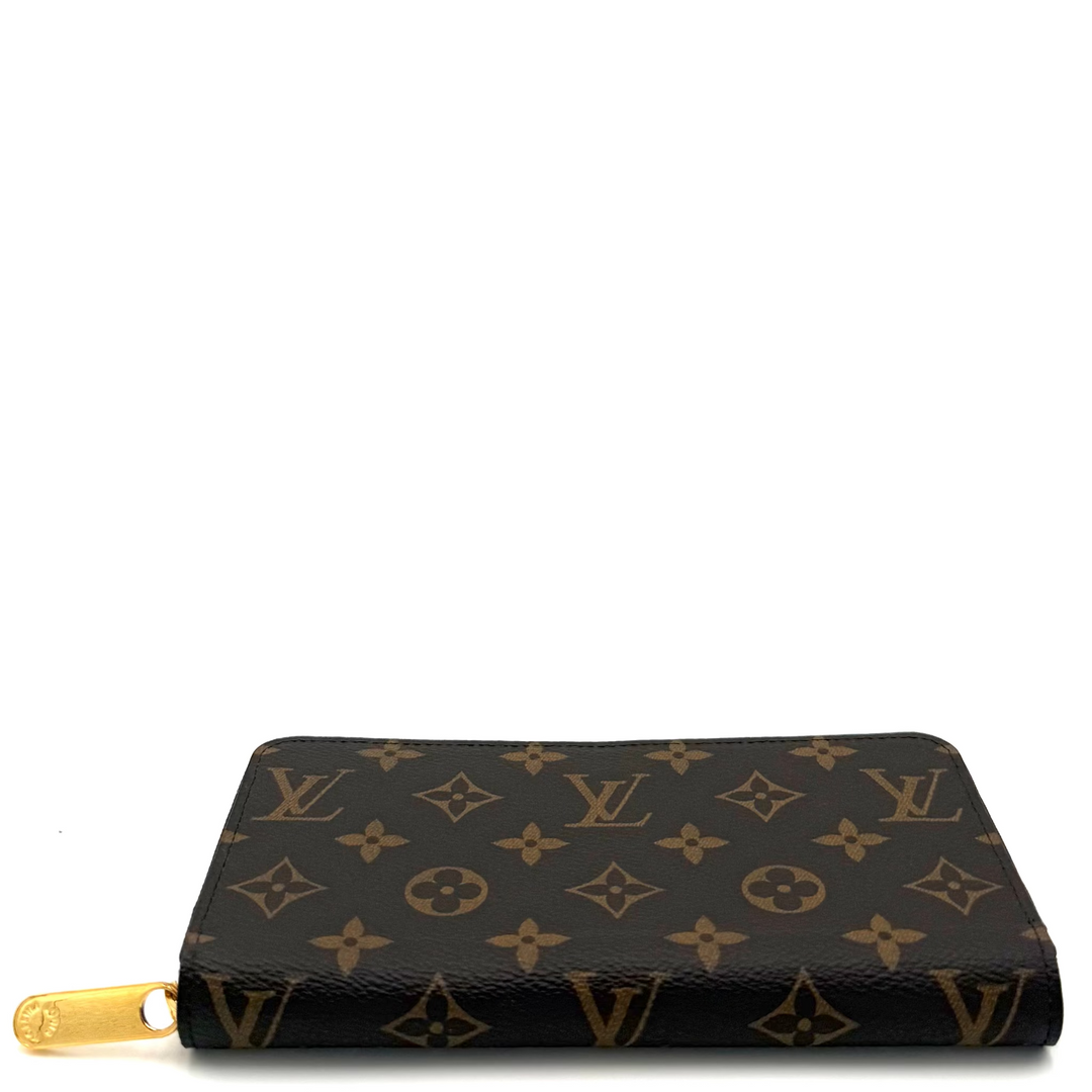 A Louis Vuitton monogram canvas zip-around wallet with gold-tone hardware, shown on a plain white background.
