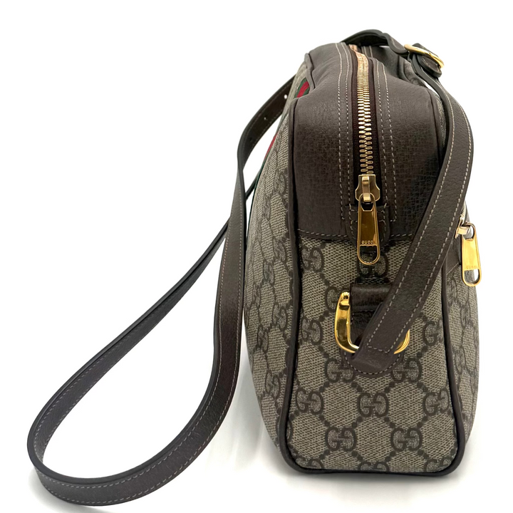 A Gucci crossbody bag in GG Supreme canvas with dark brown leather trim and gold-tone hardware, shown on a plain white background.