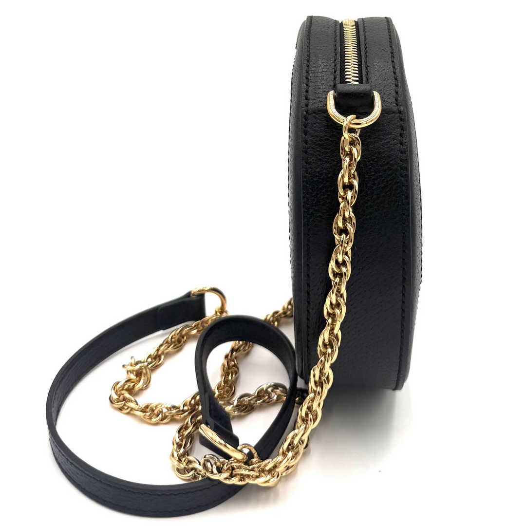 A black textured leather crossbody bag with a gold chain strap and gold zipper, shown from a side profile view on a white background.