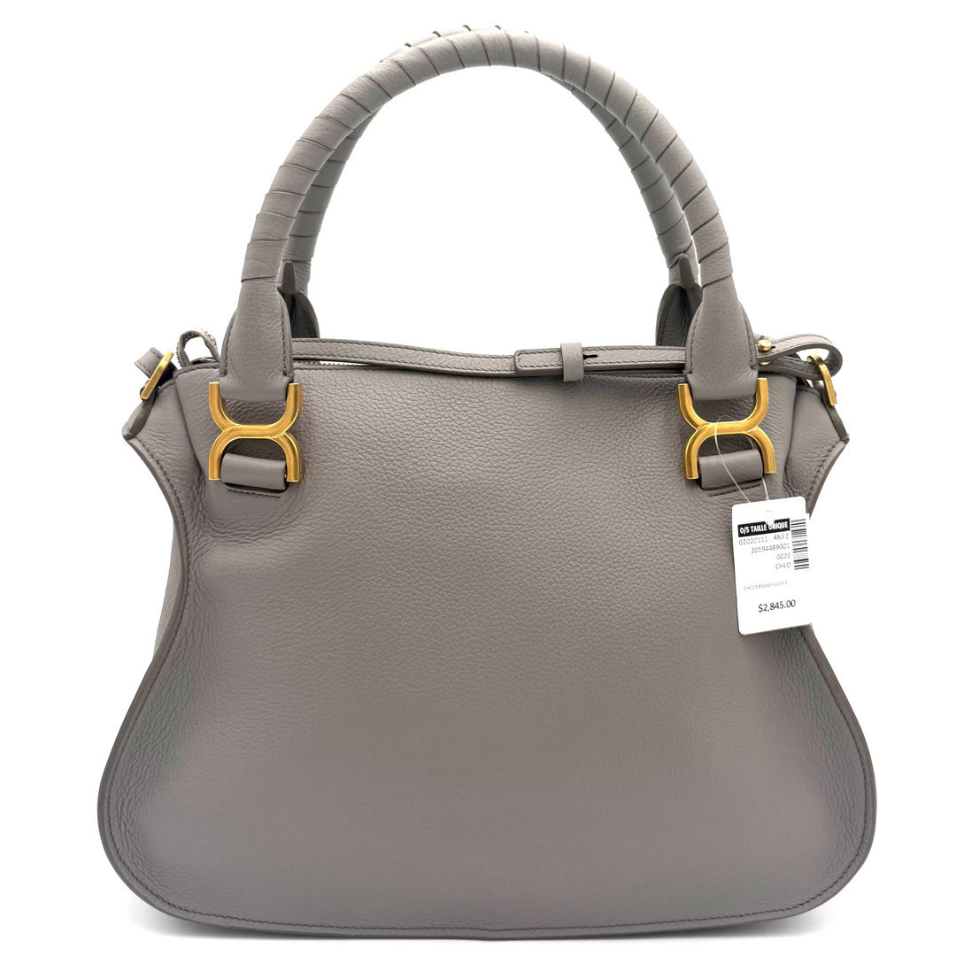 A gray leather handbag with a curved top handle, gold-tone hardware, and a white product tag, photographed against a bright white studio background.