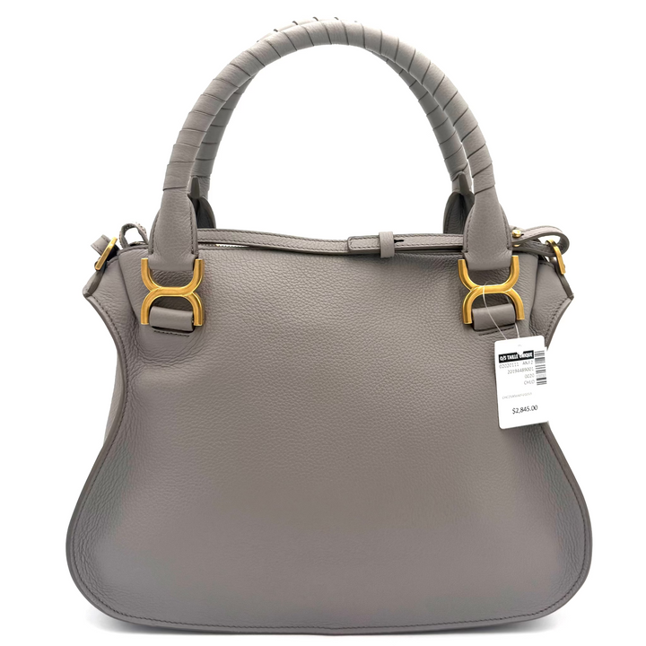 A gray leather handbag with a curved top handle, gold-tone hardware, and a white product tag, photographed against a bright white studio background.